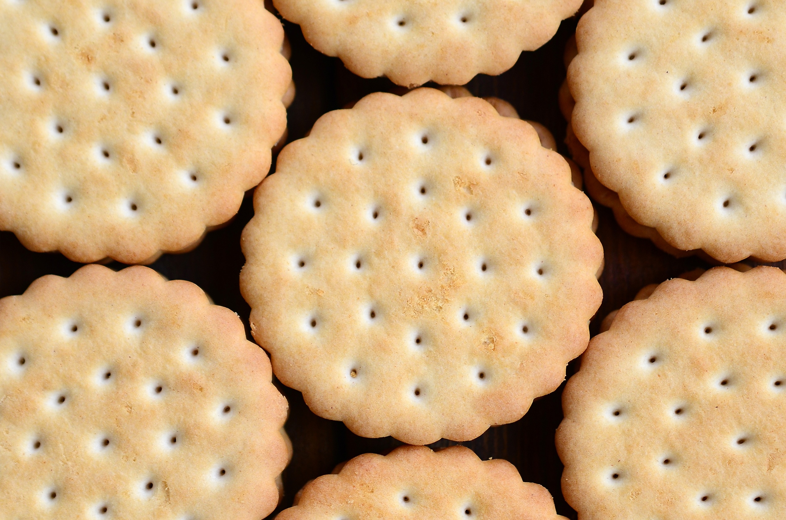 Detailed picture of round sandwich cookies with coconut filling. Background image of a close-up of several treats for tea